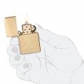 złota zapalniczka Zippo w dłoni z białymi napisami złota zapalniczka Zippo w dłoni z białymi napisami