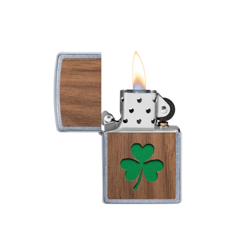 odpalona zapalniczka z jasnym płomieniem nad chromowanym korpusem i naturalnym akcentem koniczyny