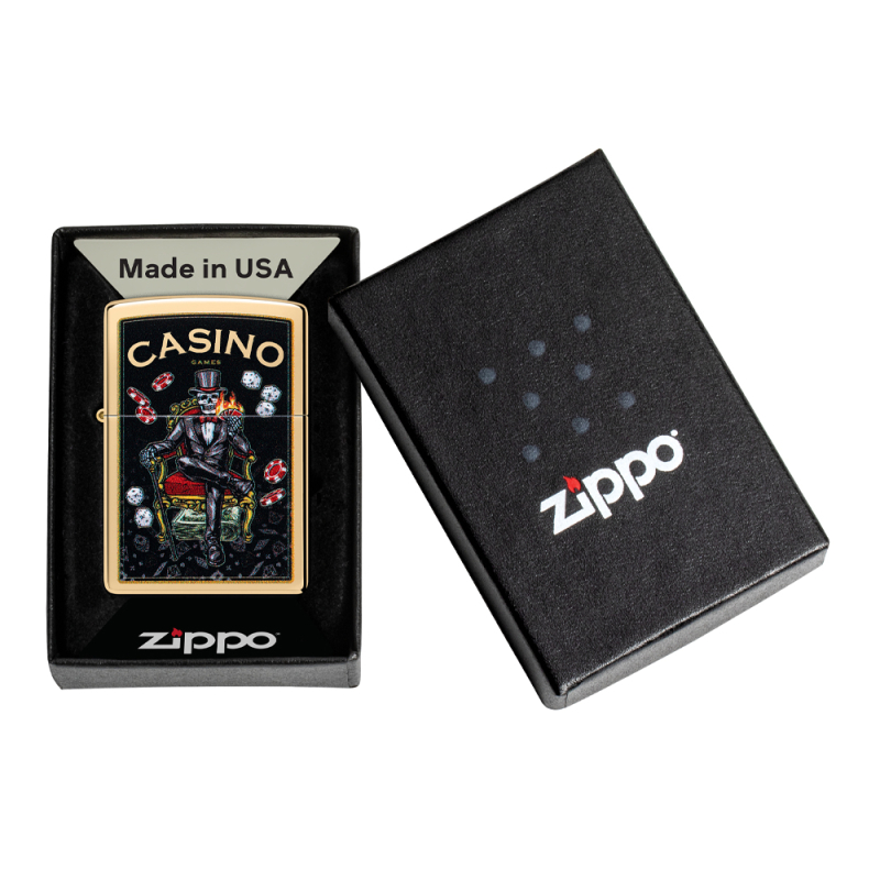 Metaliczna Zippo w złotym kolorze znajdująca się w pudełku z kontrastową grafiką inspirowaną kasynem