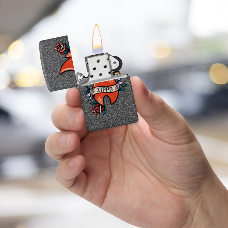 Popielata zapalniczka Zippo z tatuażowym logo prezentowana w dłoni